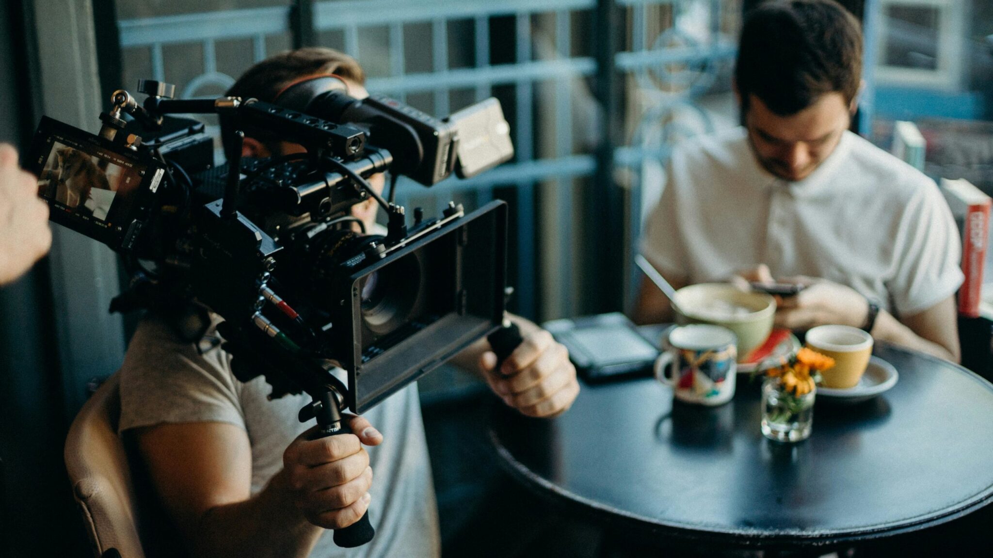 Cameraman filmant dans un café, personne utilisant un téléphone.