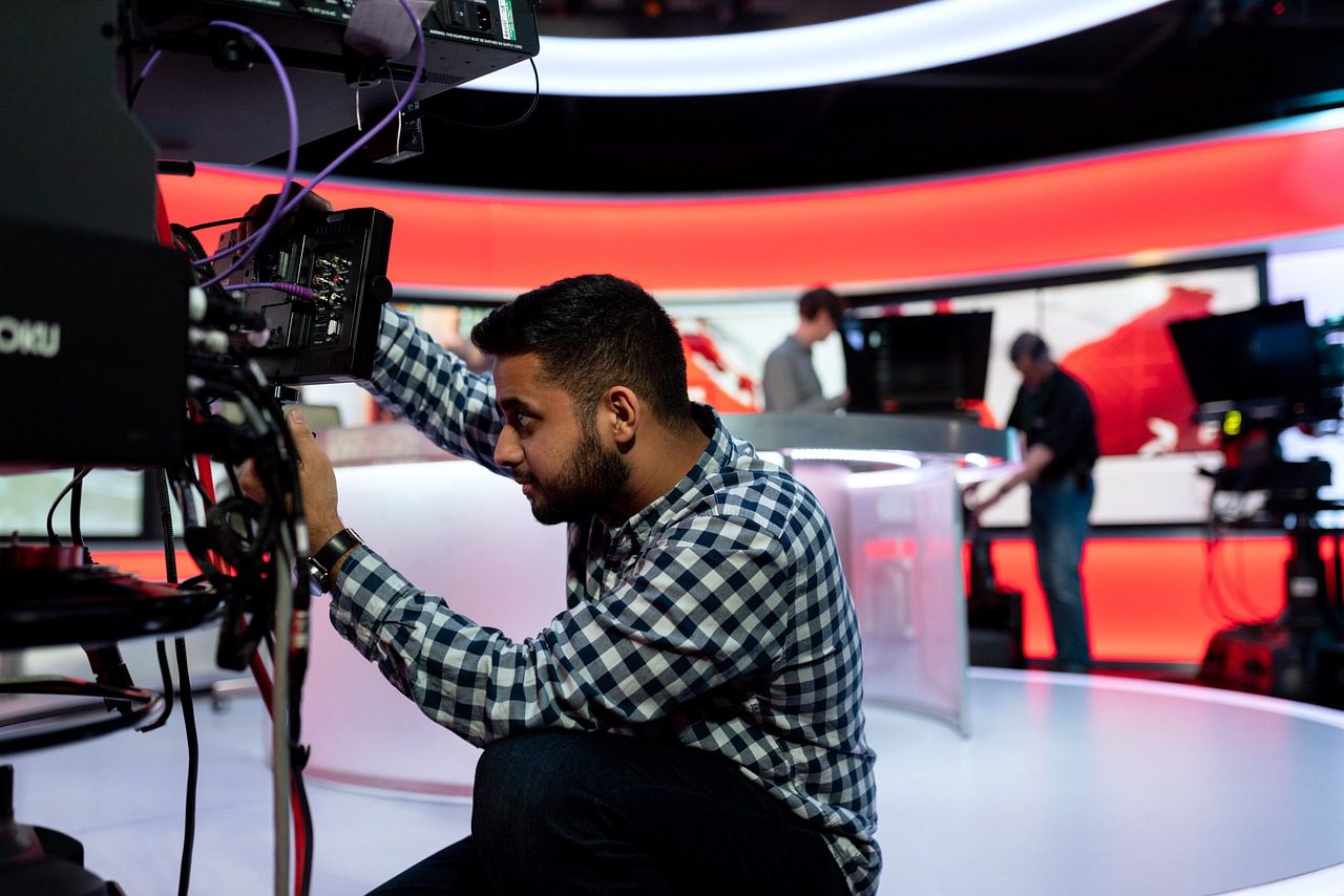 Technicien ajustant équipement dans un studio télévisé.